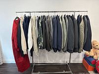 Full view of all clothing items hanging on garment rack, showing assortment of sweaters, blazers and jackets in various colors and fabrics.