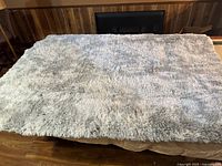 Full view of the fluffy light-colored surface of the large rectangular floor rug spread out on the floor.