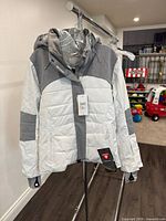 Frontal view of white and grey Roxy jacket with hood and tags visible
