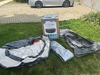 Inflatable hot tub basin, ground mat, mesh cover laid out on grass next to original box with Simple Spa branding visible.