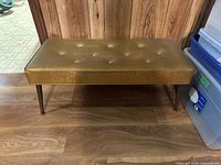 Photo of gold tufted upholstered vintage bench with wooden legs from front