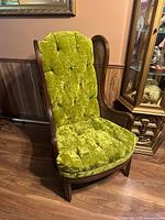 Front view showing tufted green velvet upholstery and wood frame