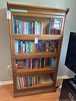 Full front view of the four-shelf barrister bookcase with books inside and auction tags attached