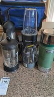 Full overview of all items including NutriBullet blender base, blender cups, Bodum coffee plunger, stainless steel thermal carafe, Stanley bottle, and blue cooler bag.