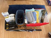 Full lot overview with body pillow, baskets with towels, electronic devices, and umbrella on floor.