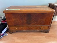 Front view of wooden chest showing wood grain, bottom drawer, and overall shape.