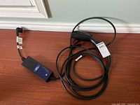 Portable EV charger laid on floor with Ford branded control box and cable coiled beside it.