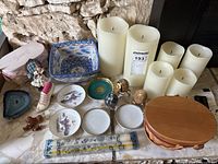 Wide view showcasing six faux candles, assorted trinket trays, decorative eggs, small figurines, and a wooden lidded basket on a marble surface.