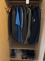Wardrobe view with jackets, shirts hanging, hats, sunglasses and shoes on shelf below