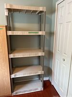Front view of the resin shelving unit with five shelves against a wall.