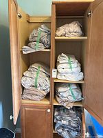 Multiple folded sheet sets and duvet stored in wooden cabinet