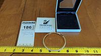 Photo showing Swarovski box, bangle, and a measuring tape indicating approximately 2.5 inch diameter.