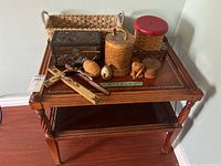 Full view of the small wooden side table with assorted wooden and rustic decor including boxes, eggs, figurines, and small baskets.