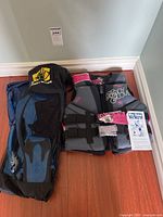 Overview of Body Glove life vest, snorkel fins bag, and strap laid on hardwood floor