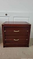Front view of the 2-drawer dresser showing dark cherry finish and brass handles with corner accents