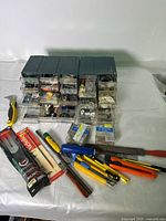 Photo showing multiple green organizer drawers filled with hardware and various hand tools including utility knives and files.