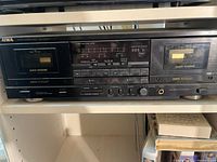 Full front view of Aiwa dual cassette tape deck showing cassette wells, control buttons, tape counter, meters, and labels.