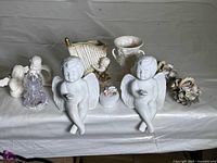 Overview of several angel and cherub figurines along with floral decor and a small vase