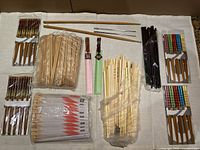 Overview photo showing multiple sets of assorted chopsticks in various materials and packaging styles spread on white cloth.