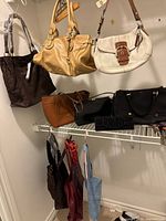 Overview of nine assorted handbags hanging and on shelf