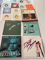 Overhead photo of several vinyl records and 45 rpm singles spread out. Includes The Smiths 'The Queen is Dead', Beethoven 9 symphonies boxed set, The Orchestra, Dirty Dancing soundtrack, and multiple 45s with varied label designs.