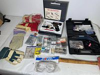 Full spread of lot contents including gloves, tool cases, fasteners, safety goggles, and mallet on white surface.