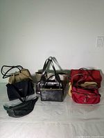 Nine assorted handbags arranged on a flat surface showing front and side views with varied colors and styles.