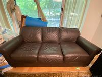Front view of the brown leather couch, showing three seat cushions and the natural leather texture with minor wear.