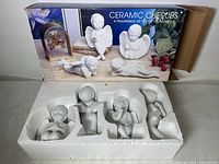 Four white ceramic cherub figurines inside original foam insert and retail box.