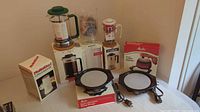 Photo showing all items boxed together: MultiChef coffee & spice mill, Bodum Bistro 8-cup French press, Melior French press, two Melita coffee warmers.