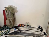 Overall view of two golf bags, mixed clubs laid out on table, baskets of balls and accessories