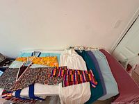 Overview of Hanbok garments including Jeogori jackets, norigae-style sash, and long Chima skirts in various colors laid out on a table.