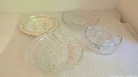 Four heavy, thick glass platters including one round geometric, one round concentric circle, one divided serving platter, and one oval segmented platter on flat surface