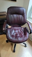 Front view of dark brown leather office chair showing padded seat, backrest, and armrests.