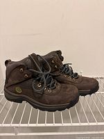 Side view of a pair of brown Timberland hiking shoes showing leather upper, logo, and laced closure with metal eyelets.