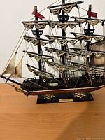 Side view of the model tall ship showing details of masts, sails, rigging, and hull on wooden display base.
