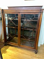 Front view showing double glass doors with geometric wooden mullions and bun feet