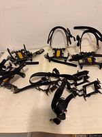 Wide shot showing two pairs of Simond RAPTOR crampons with steel frames, front and side points, and adjustable black strap bindings, alongside one pair of metal instep crampons with rubber straps.
