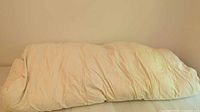 Photo of the folded off-white down duvet showing the general size and condition with creases and wrinkles.