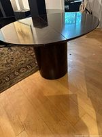 Full view of round table on cylindrical pedestal base with leaf inserted