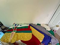Multiple jeogori jackets and hanbok skirts and pants laid out on bed showing colors and fabric patterns.