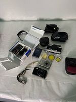 Overview of all cameras and accessories laid out on table, showing film camera, digital cameras, charger, cases and filters