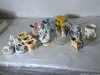 Full view of all vintage ceramic items including figurines, baby bootie planters, a yellow school bus coin bank, floral baskets, and small vases.