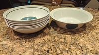Six vintage English ironstone bowls with teal and gold medallion inside, one bowl shows exterior detail, arranged on a countertop.