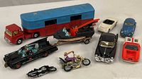 Collection of diecast toy cars including the Corgi circus trailer, Batman and Robin Batmobile with Bat Boat, motorcycles, Lotus, and other cars.