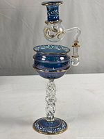 Full view of the hand made Egyptian blue and clear glass essential oil diffuser with gold and white painted decorative accents.