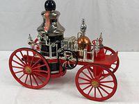 Full view of the Jim Beam 1867 Mississippi Fire Engine decanter showing the red wheels, silver and copper details, and bottle stopper.