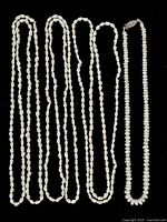 Four Keshi pearl necklaces laid flat on a black surface showing all strands.