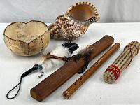Showing the painted gourd bowl, natural sea shell, flute, rain stick and feather wrist decoration arranged for clear view.