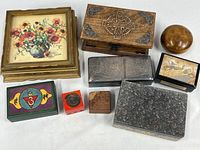 Group of nine lidded boxes of various sizes and materials displayed together on white surface.